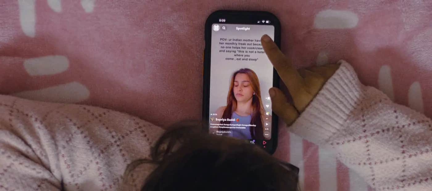 A person lying on a pink blanket, privately scrolling through messages on their phone